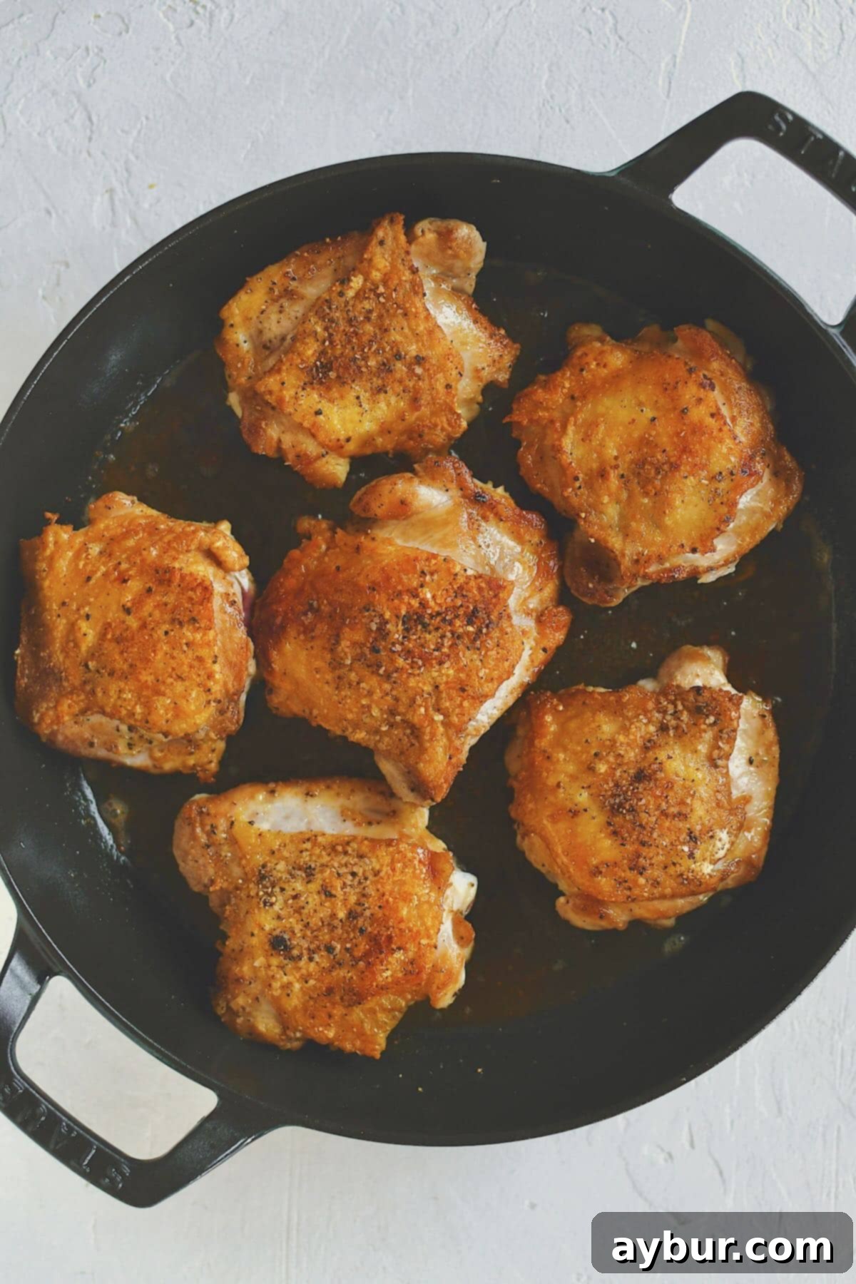 Caramelized French Onion Chicken 4 Perfectly crisped bone-in, skin-on chicken thighs in a large skillet, ready to be removed before caramelizing onions.