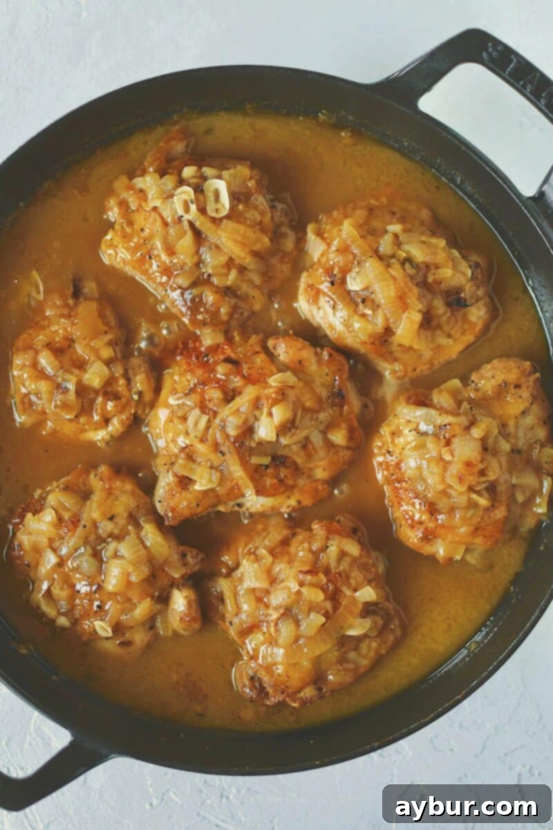 After the chicken has cooked in the sauce, topping it with the caramelized onions in preparation for cheese.