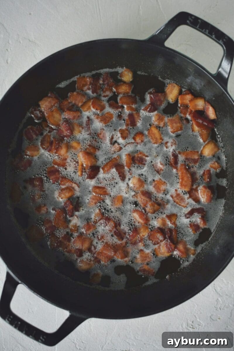 Diced bacon crisping in a large skillet.