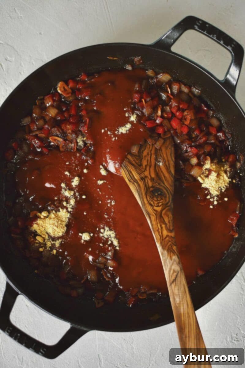 Stirring in the seasonings and bbq sauce to the veg before adding the beans.