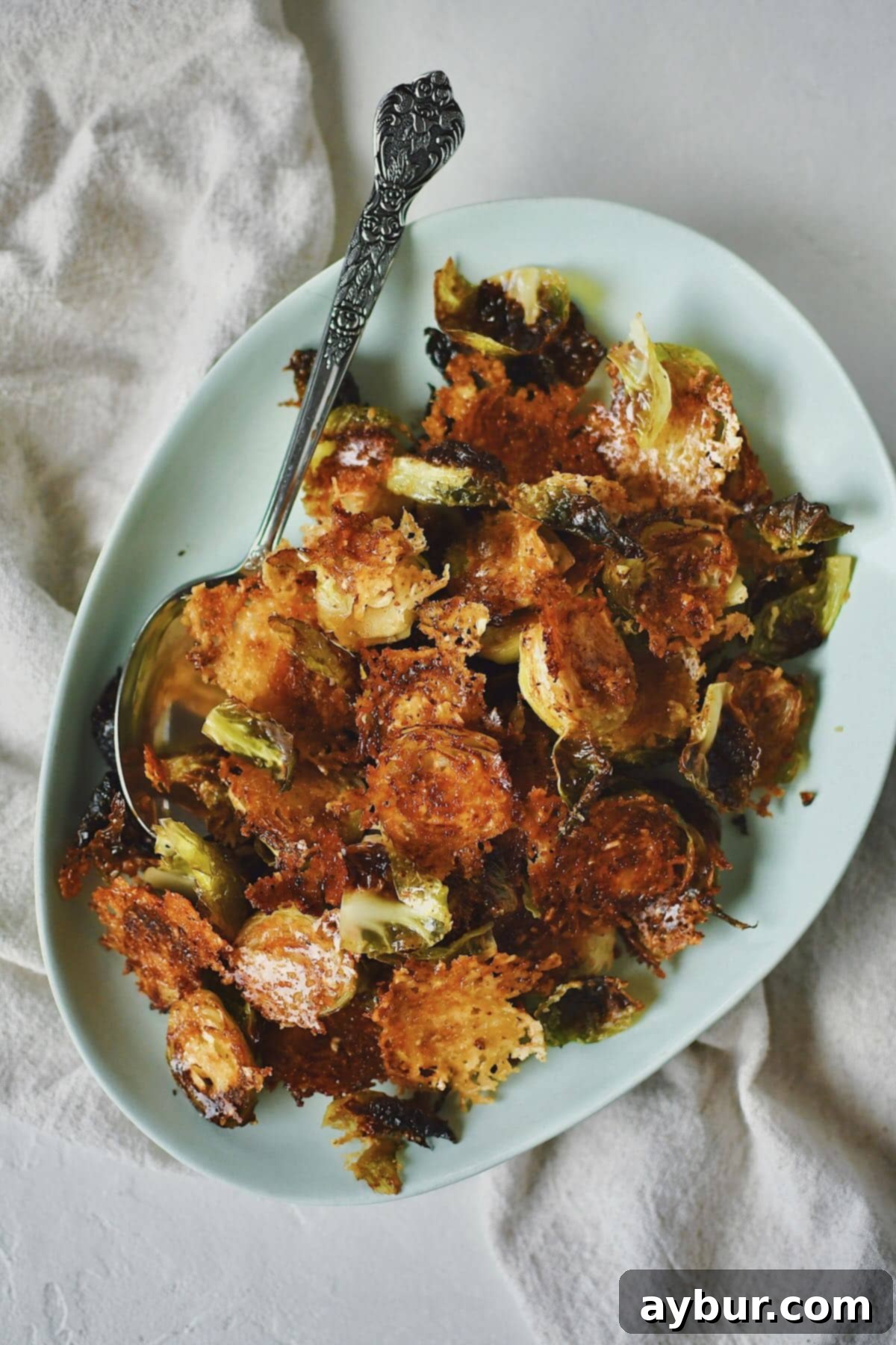 Close-up of a serving of crispy Parmesan Brussels sprouts, perfectly golden brown and topped with fresh herbs, ready to be enjoyed.
