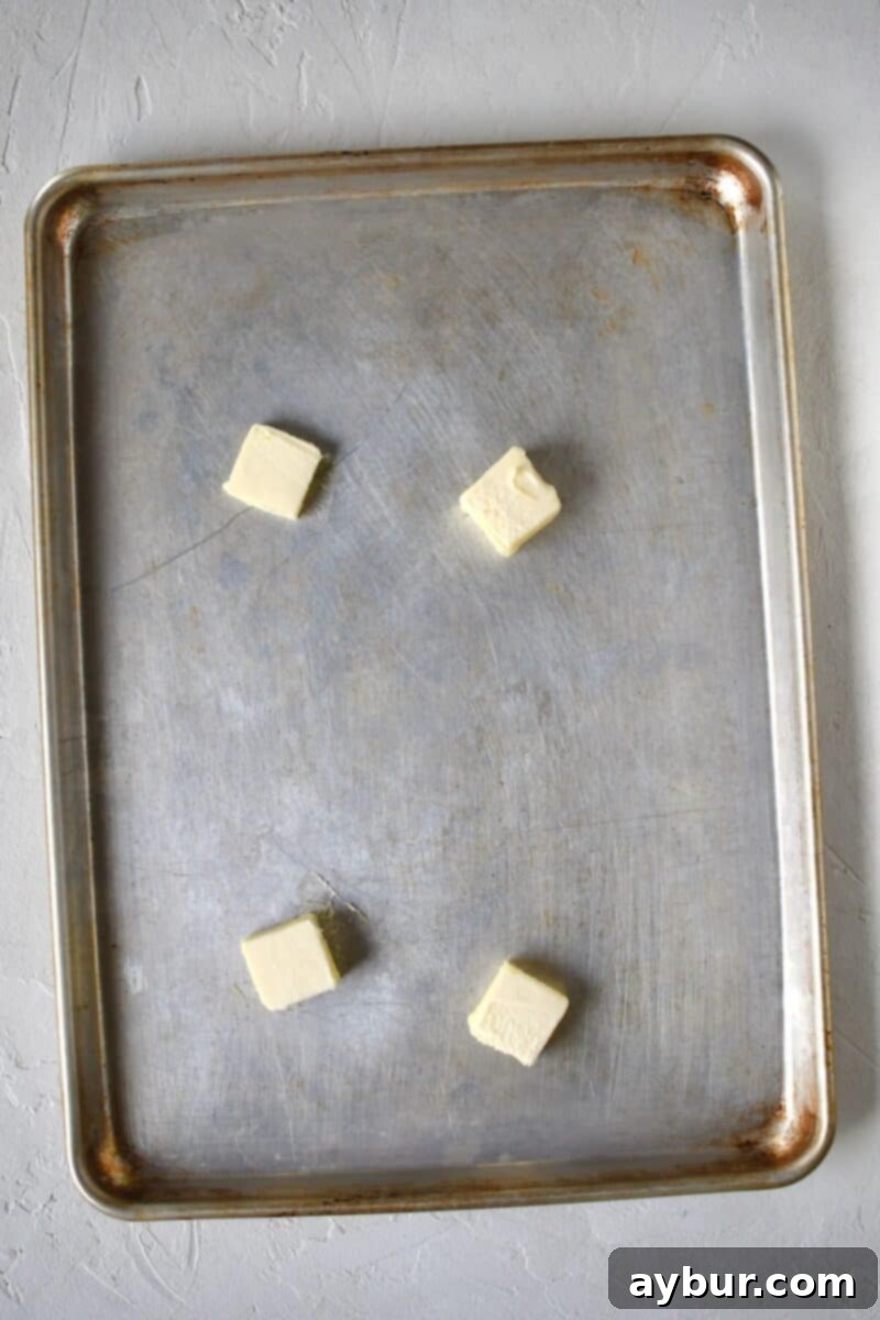 Unsalted butter melting on a baking sheet in the oven, ready for the Parmesan layer.