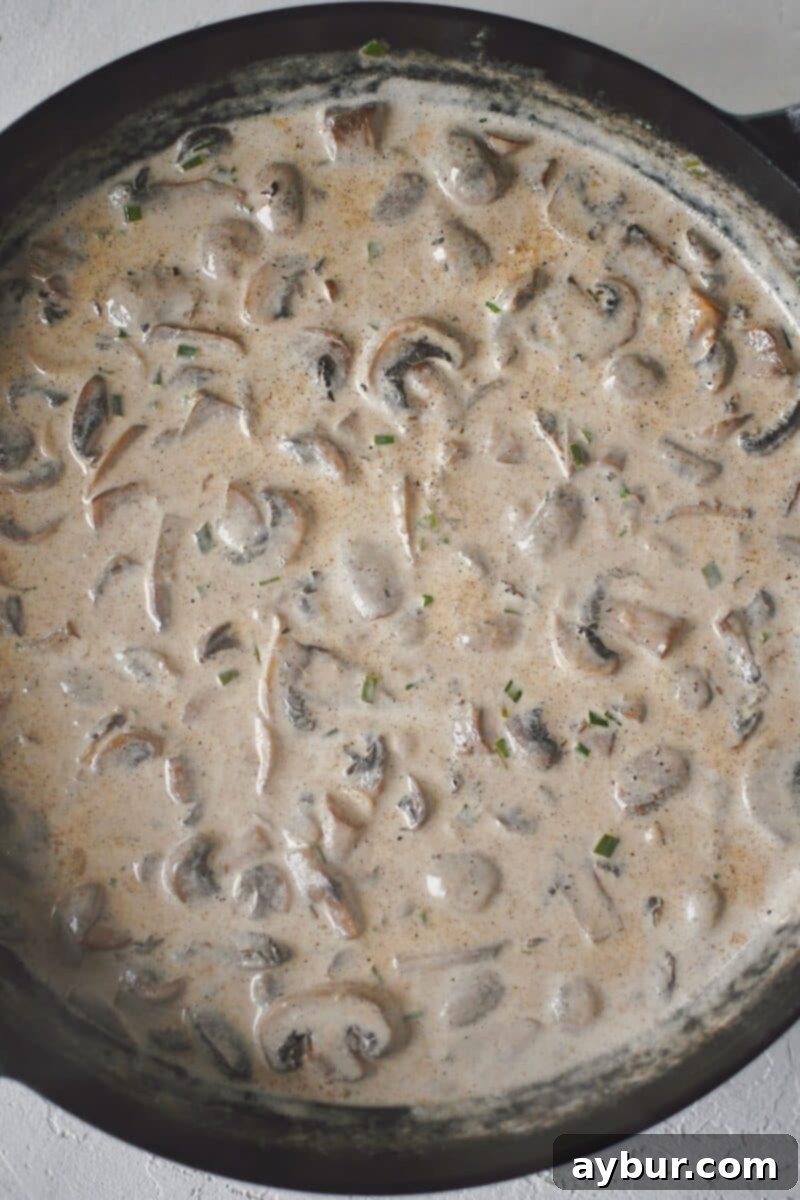 Velvety Mushroom Chicken 9 The creamy sauce simmering in the skillet, thickening to a luscious consistency.