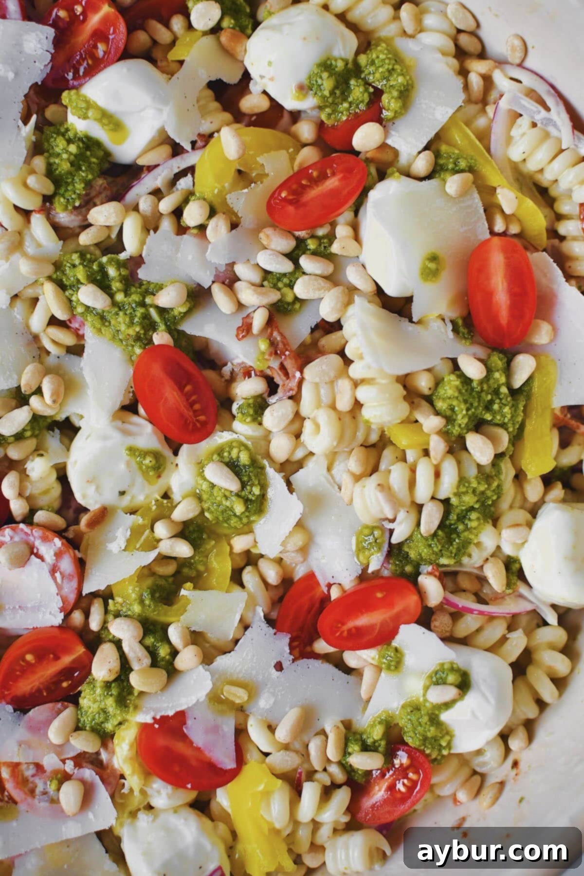 Another beautiful shot of the Pesto Pasta Salad with fresh pesto, shaved parmesan, and pine nuts, in a large serving bowl.