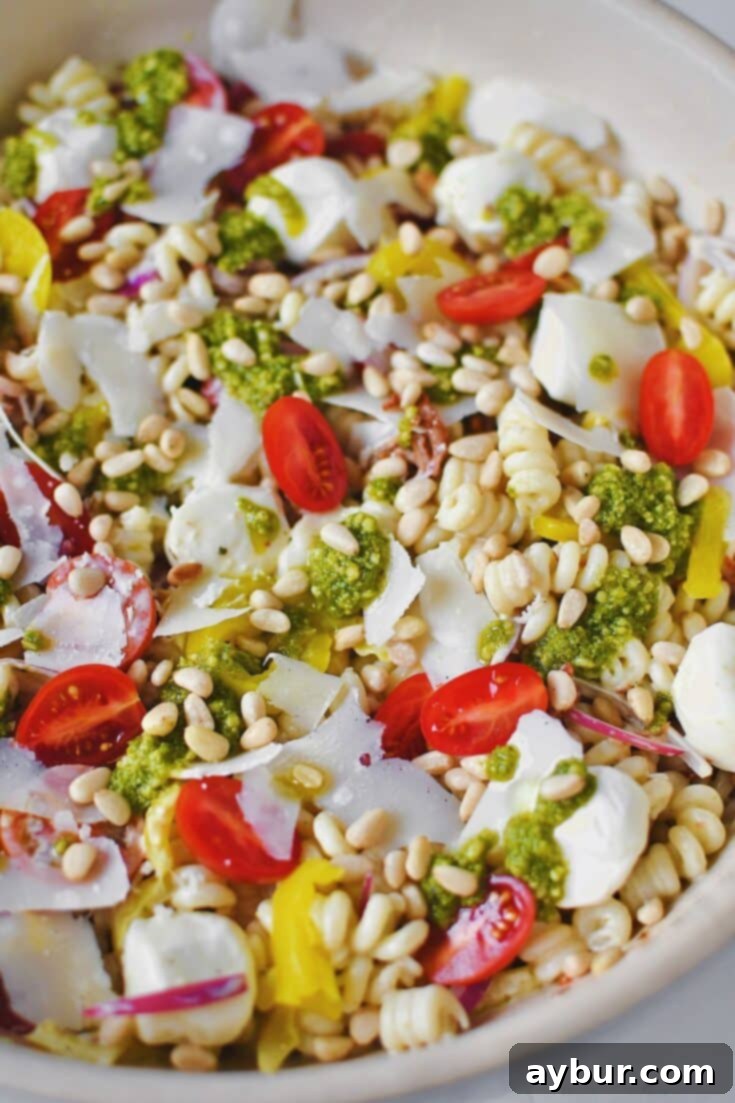 Fully dressed Pesto Pasta Salad topped with pesto and freshly shaved parmesan before serving.