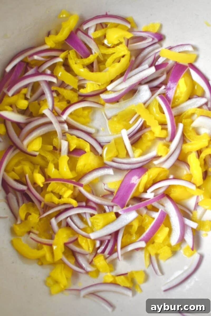 Rough chopped banana peppers and finely sliced red onions in a bowl, marinating in white balsamic vinegar.