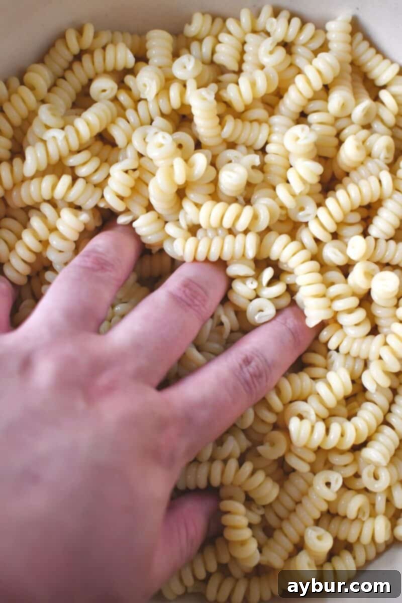 Cooled, rinsed pasta added to the bowl with the marinated peppers and onions.