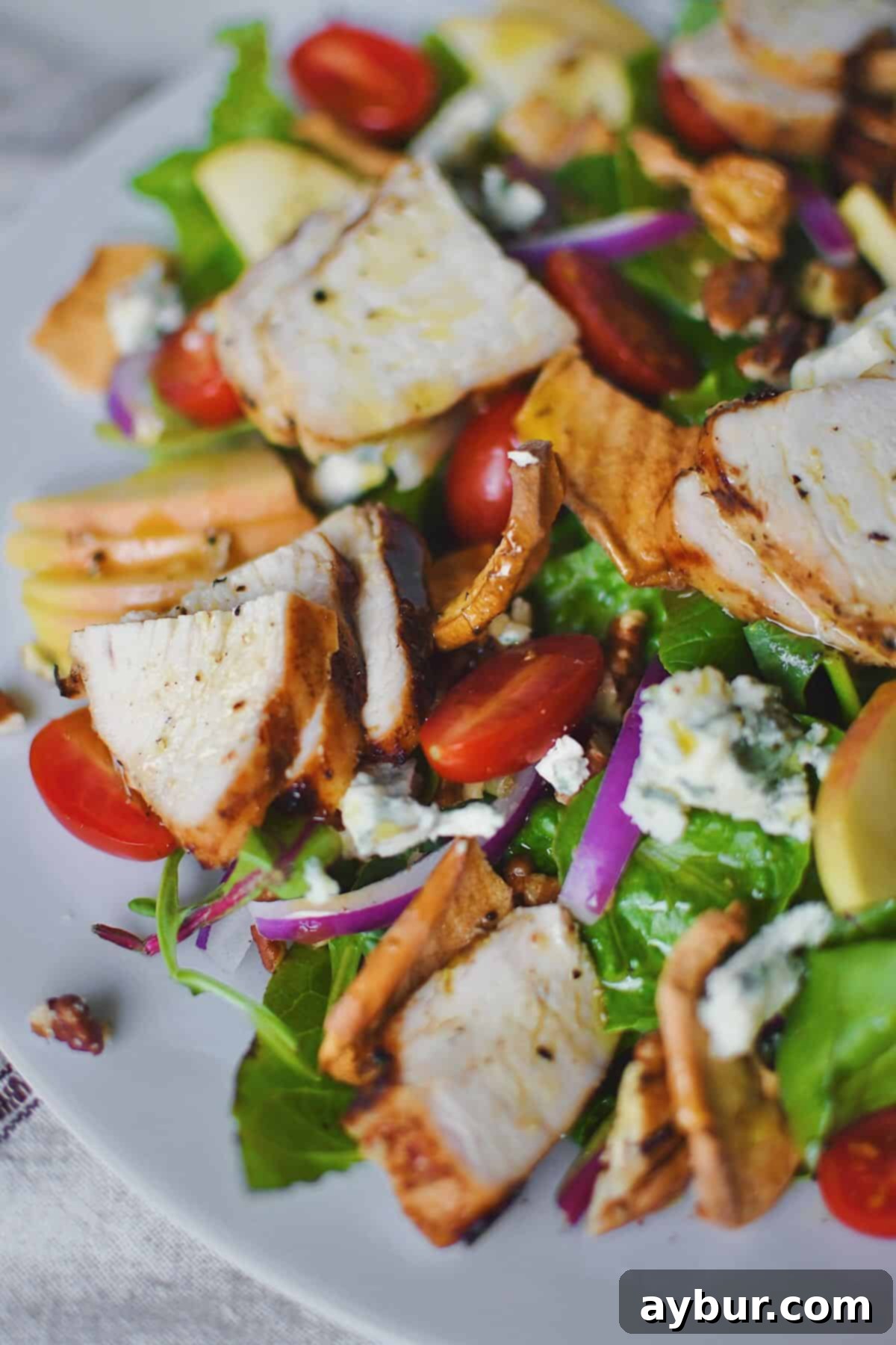 Homemade Panera Fuji Apple Salad topped with perfectly grilled chicken, on a white plate, ready to be enjoyed.