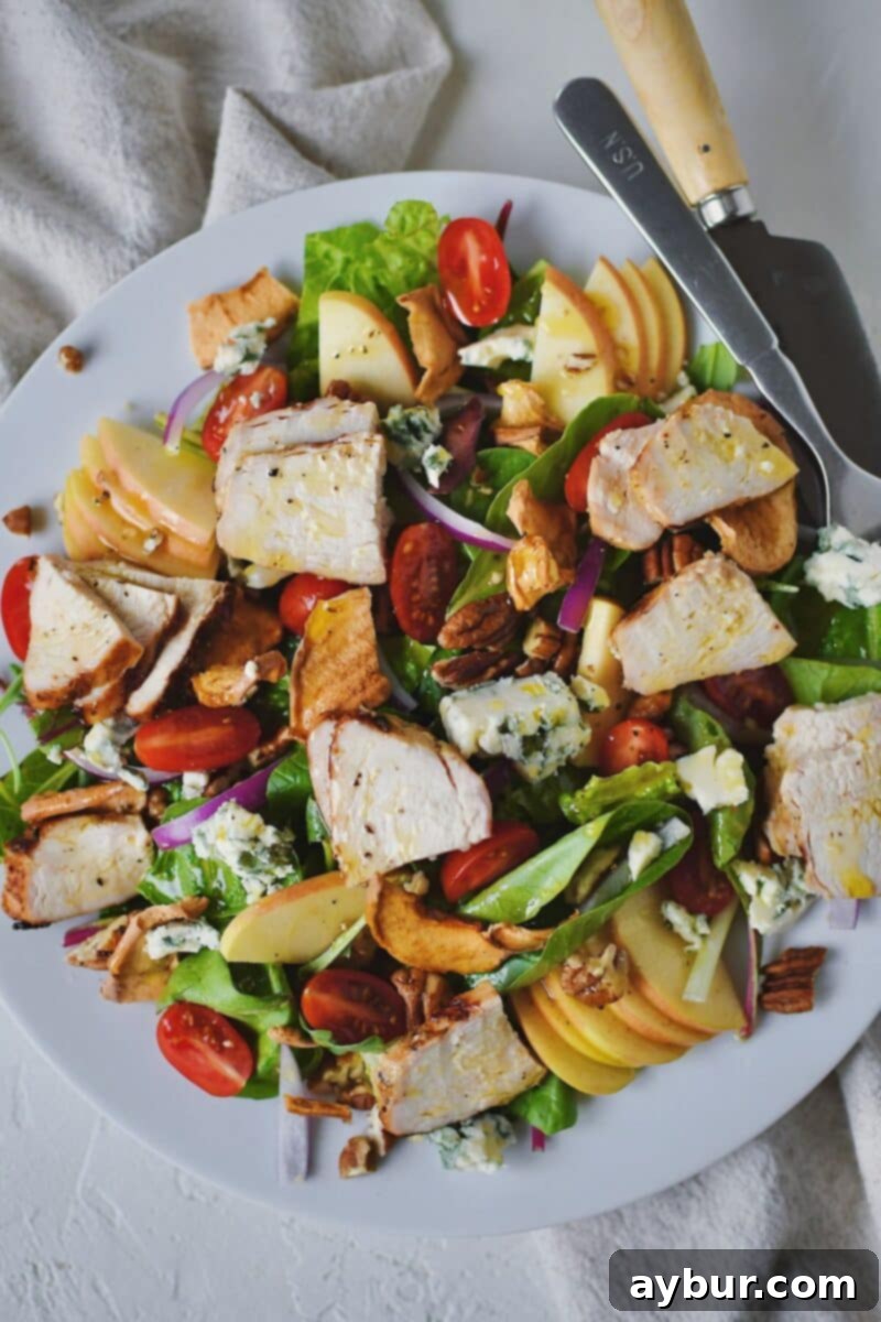 A freshly assembled Panera Fuji Apple Salad, topped with chicken and all the vibrant ingredients, on a plate ready for serving.