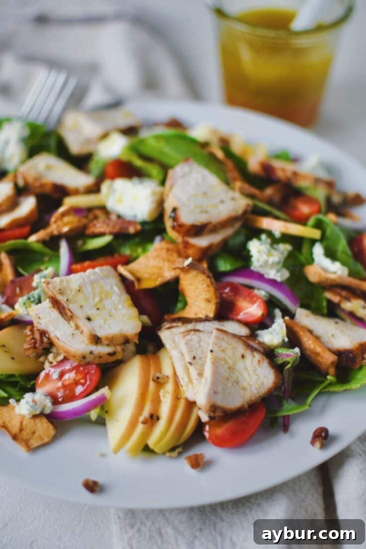 Panera Fuji Apple Salad topped with chicken, on a plate ready to eat.