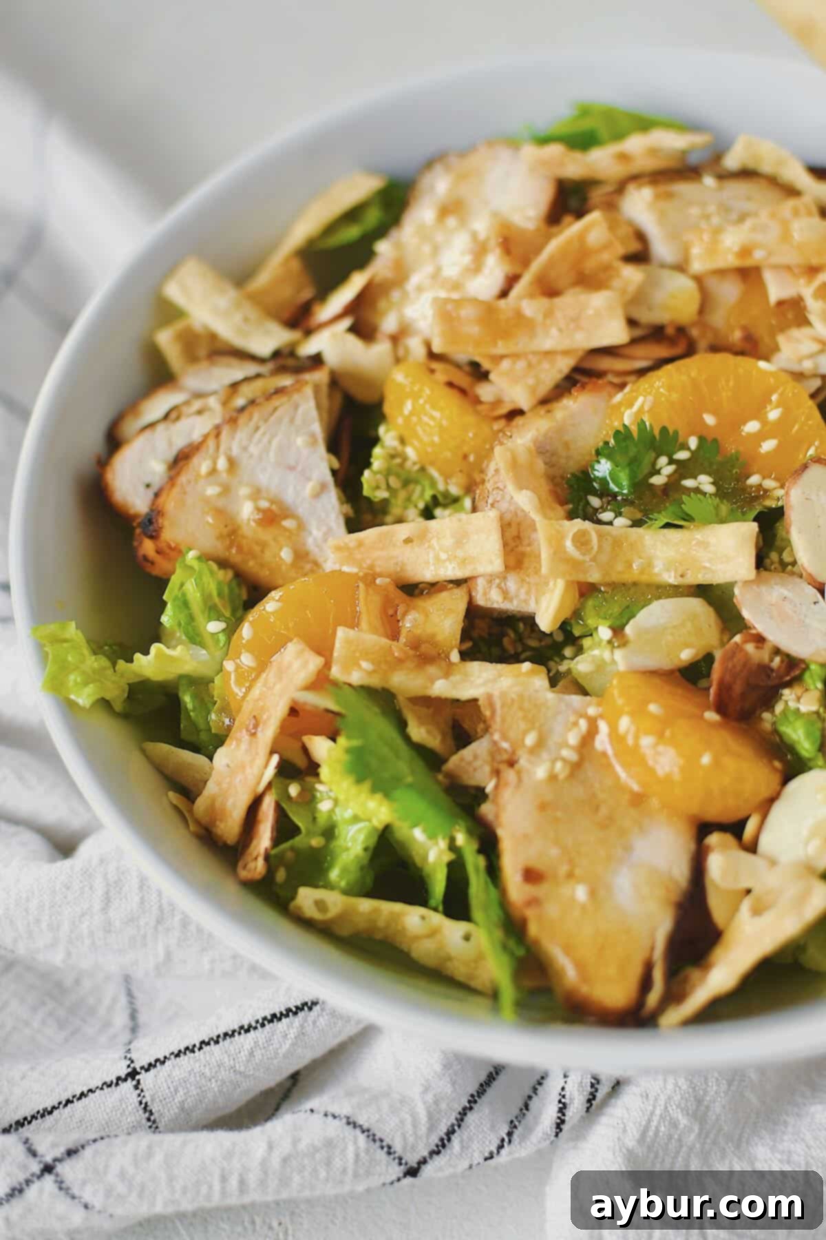 Fully dressed homemade Panera Asian Sesame Salad, vibrant and ready to eat with grilled chicken, oranges, and crispy toppings.