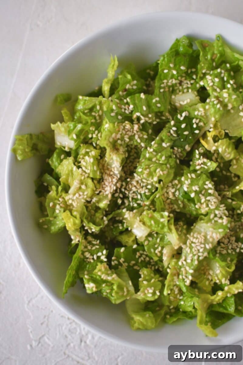 Dressed greens are placed in a serving bowl, then garnished with toasted sesame seeds for enhanced flavor and appearance.