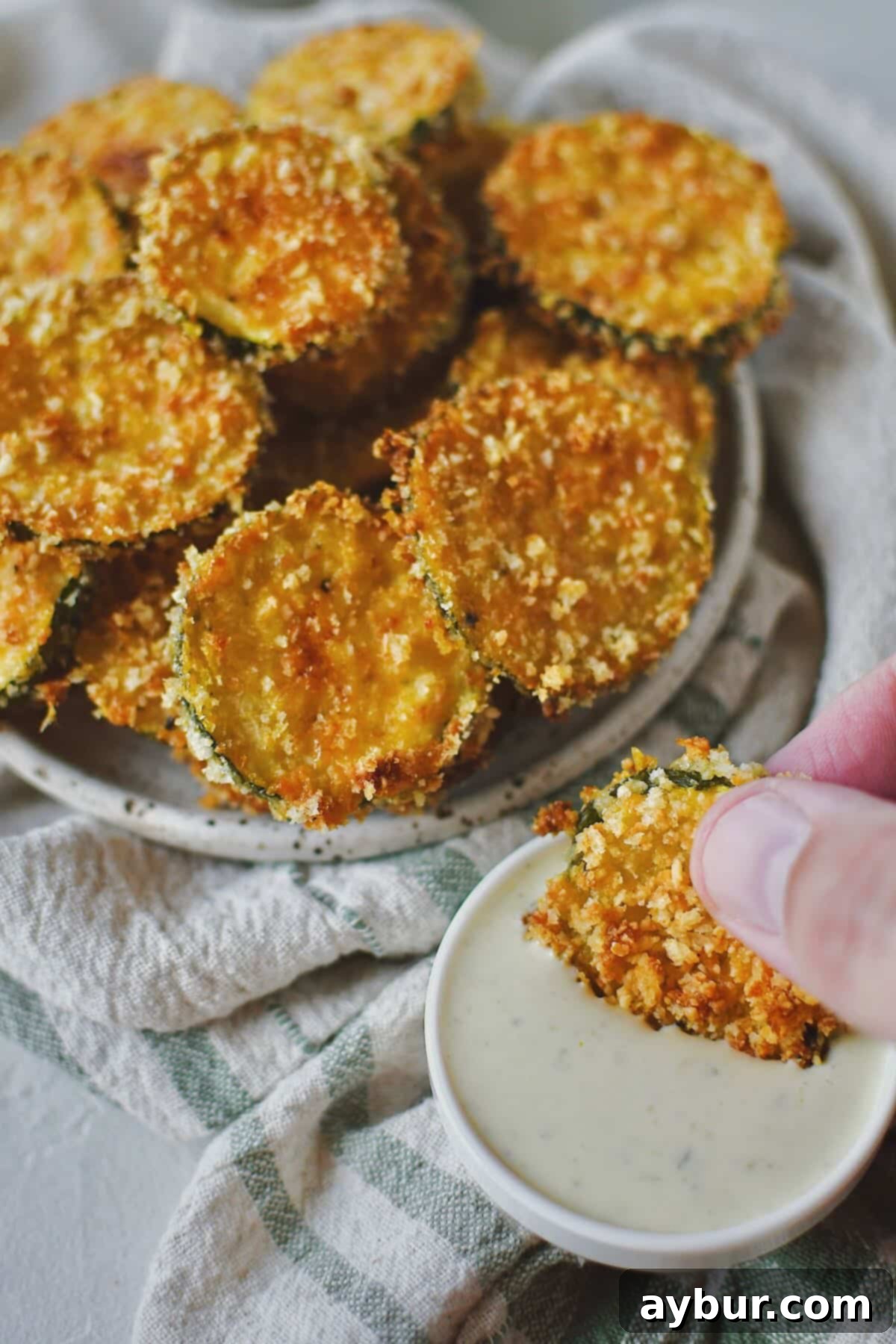 Baked Zucchini Crisps 2 A stack of golden-brown, crispy Parmesan Zucchini Chips, freshly baked and ready to be served with a creamy ranch dipping sauce.