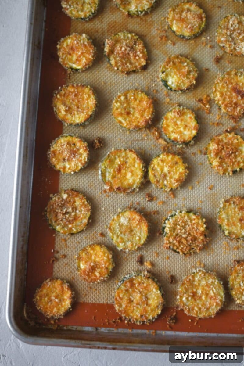 Baked Zucchini Crisps 10 A batch of golden-brown, crispy Zucchini Chips, freshly baked and glistening, just removed from the hot oven.