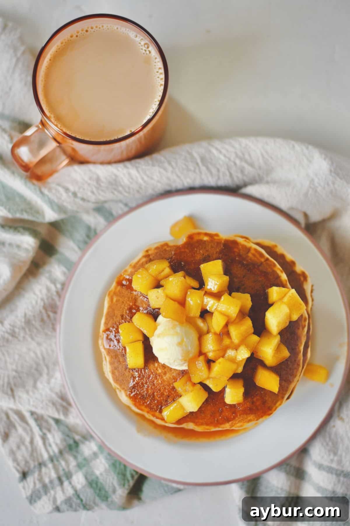 Warm Spiced Apple Pancakes 2 Stacked Apple Cinnamon Pancakes generously topped with a rich, homemade caramel apple syrup and a dollop of melting butter.