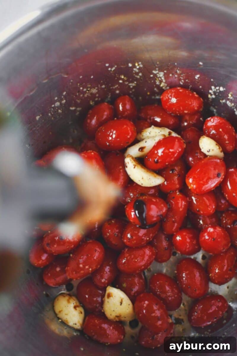 Fire-Kissed Tomato Vinaigrette 4 Tossing vibrant grape tomatoes with olive oil, salt, pepper, and aged balsamic vinegar in a bowl before roasting.