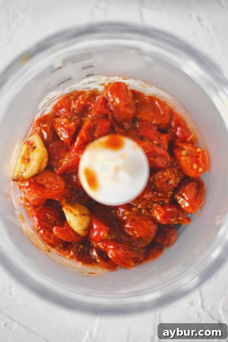 Fire-Kissed Tomato Vinaigrette 6 Transferring roasted tomatoes and garlic into a mini food processor for blending.