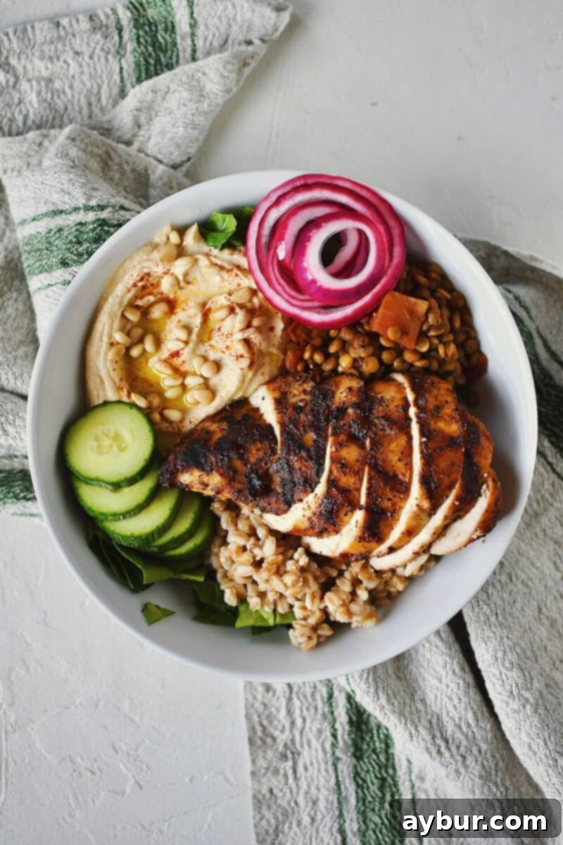 Sliced cucumbers, tangy pickled red onions, and tender chicken are added to the growing Mediterranean Bowl.