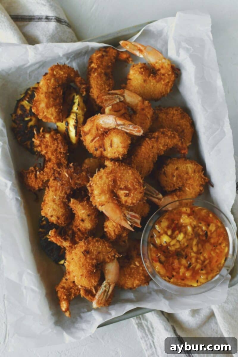 Close-up of freshly fried Coconut Shrimp, glistening golden-brown and perfectly crispy, ready to be served.