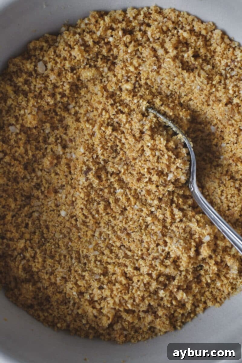 A close-up of the crust ingredients being mixed together with a fork until a sandy, cohesive texture is achieved, ready for pressing.