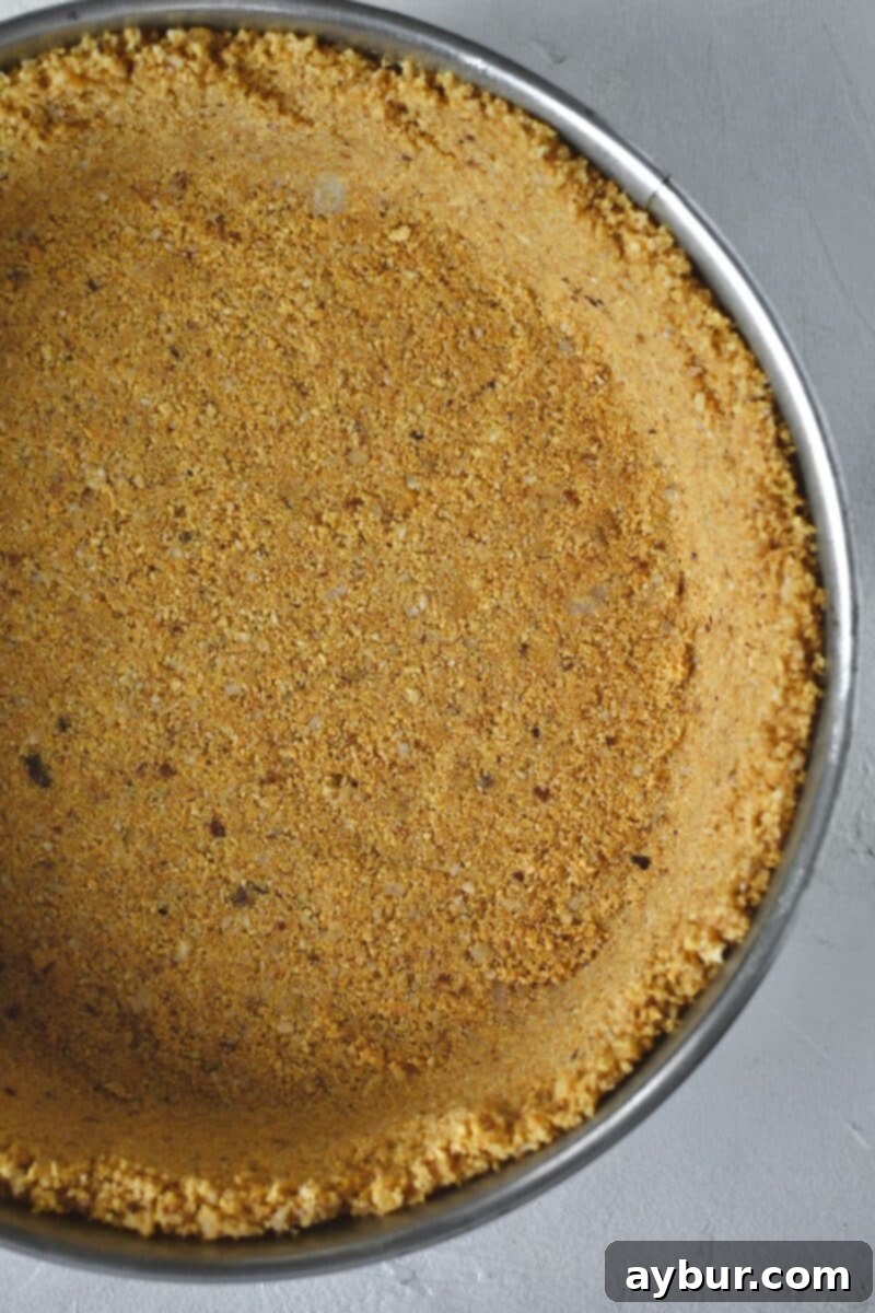 The hazelnut graham cracker crust pressed evenly into the bottom and up the sides of a springform pan, prepped for baking.