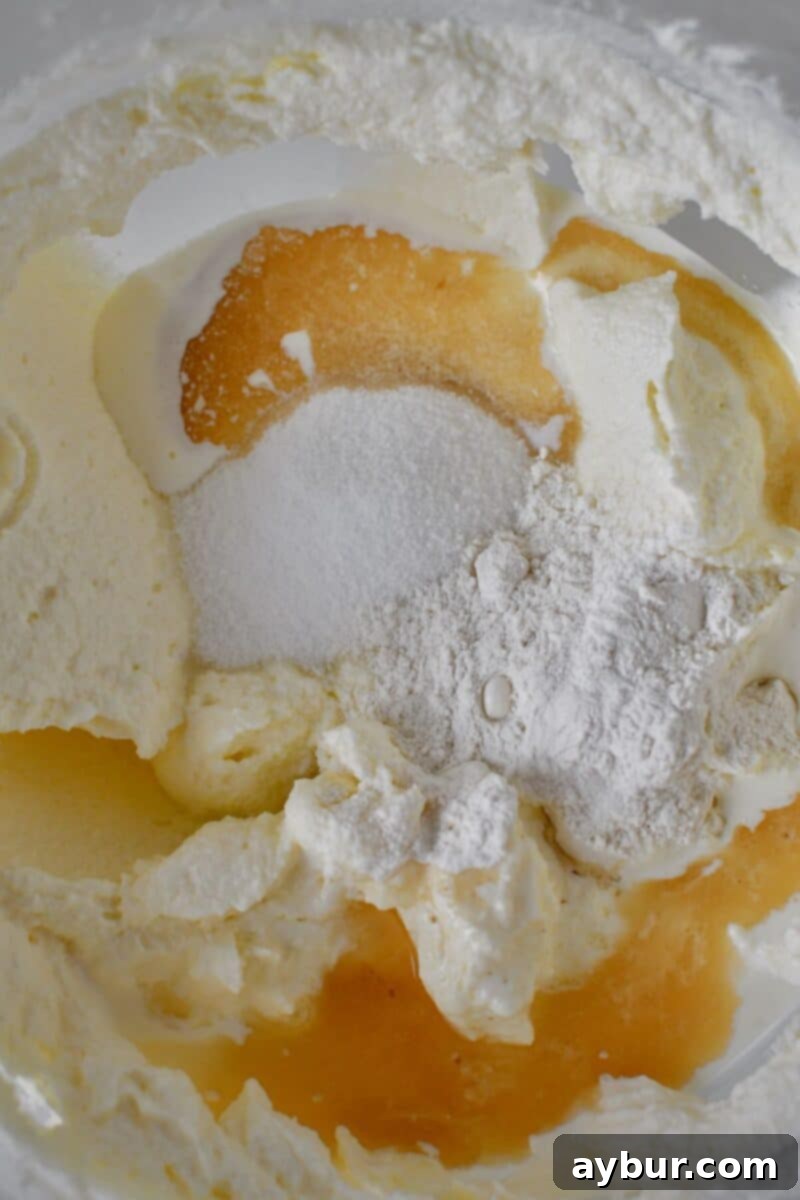 Adding granulated sugar, kosher salt, all-purpose flour, heavy cream, and vanilla extract to the creamed cheese mixture in the stand mixer.