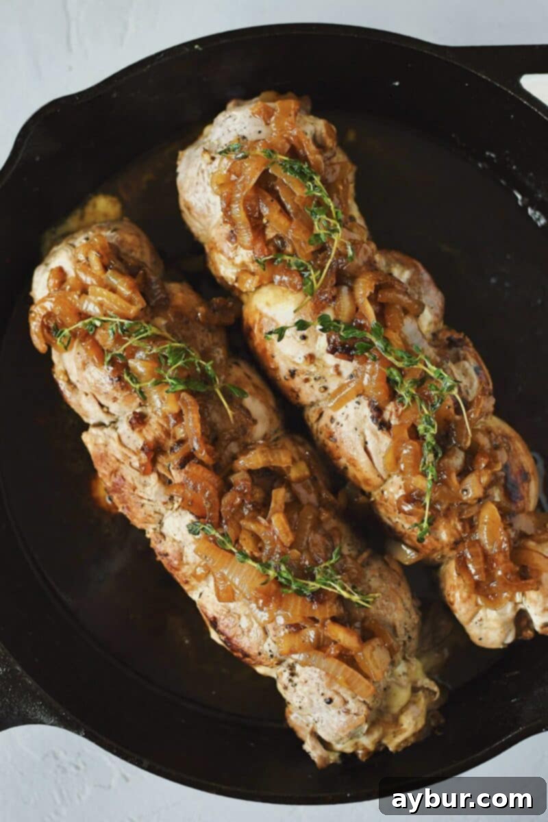 Savory Stuffed Pork Tenderloin 14 Seared Stuffed Pork Tenderloins resting in the pan, topped with extra caramelized onions and fresh thyme.