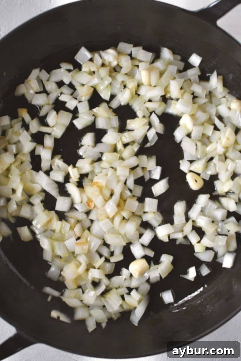 Fırında Tavuklu Brokoli Pilavı 4 Finely chopped onions are sizzling in a large skillet with olive oil, softening and becoming translucent on the stovetop.