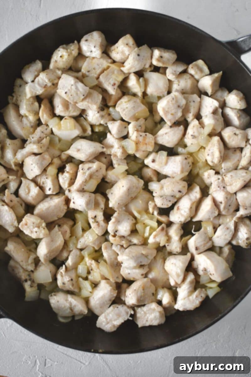 Fırında Tavuklu Brokoli Pilavı 5 Diced chicken pieces are added to the skillet with the sautéed onions and garlic, beginning to brown lightly on the edges.