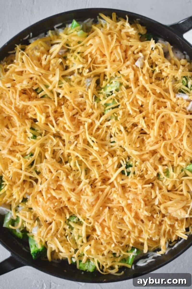 Fırında Tavuklu Brokoli Pilavı 8 Generous handfuls of shredded cheddar cheese are sprinkled over the chicken, broccoli, and rice mixture before being gently stirred in.
