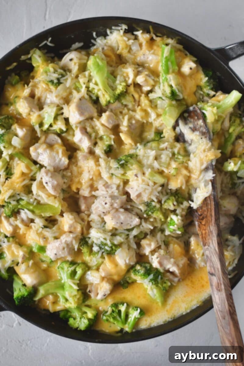 Fırında Tavuklu Brokoli Pilavı 9 The cheddar cheese has been stirred into the casserole, creating gooey pockets, and the surface is smoothed out, ready for the final toppings.