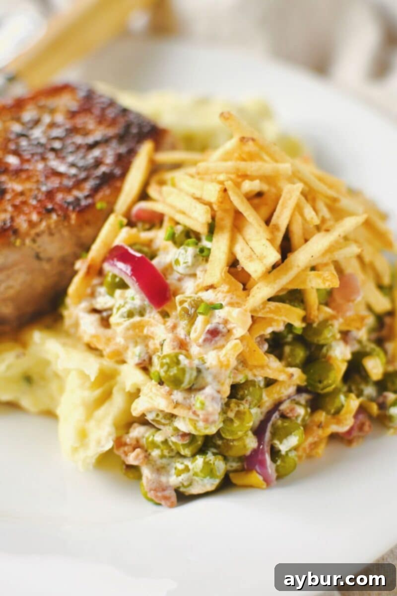 Pea Salad 9 A complete dinner plate featuring the Bacon Pea Salad served alongside succulent pork chops and fluffy mashed potatoes, highlighting its role as a perfect side dish.