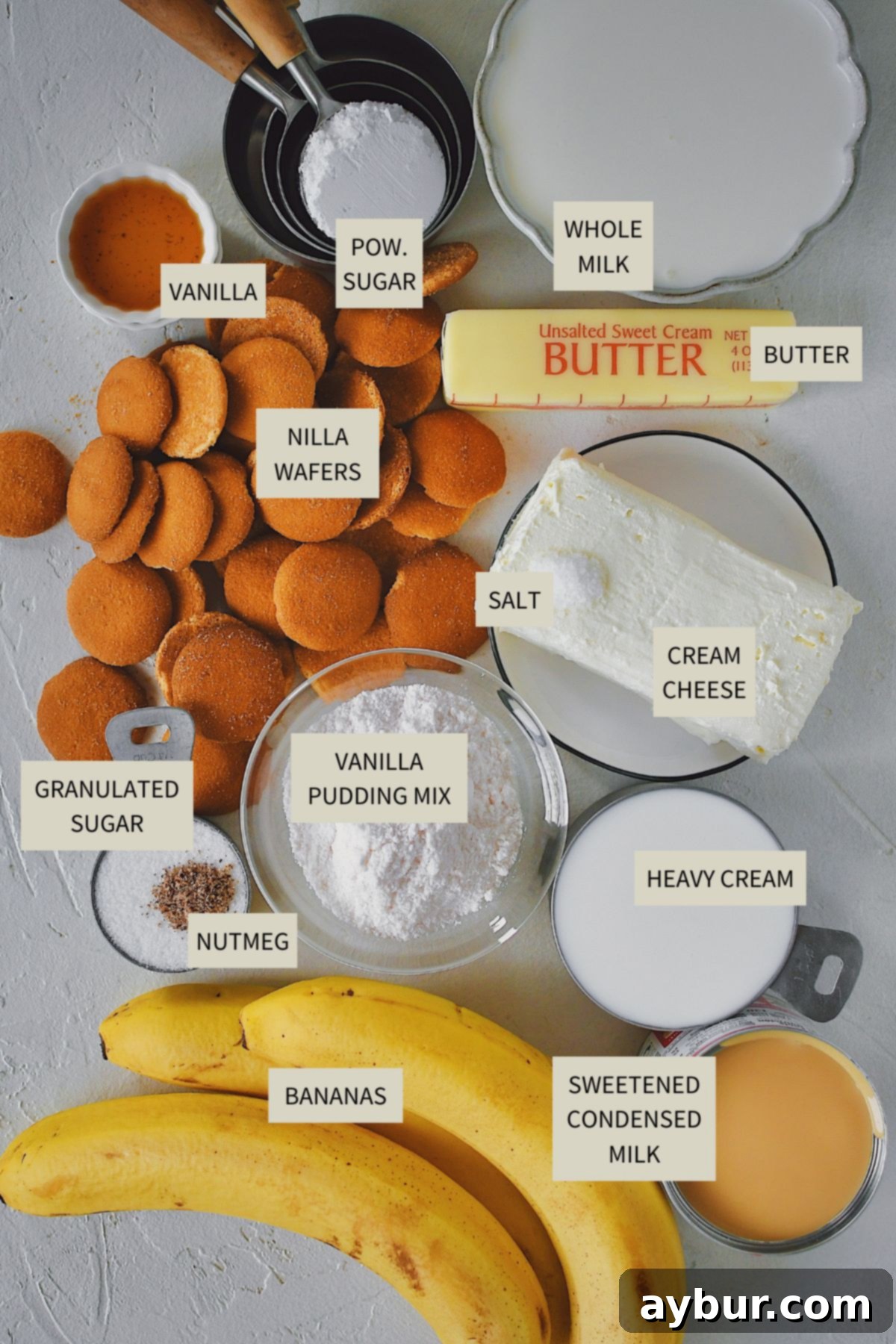 An array of fresh bananas, Nilla wafers, milk, cream cheese, and other baking essentials laid out for making Banana Pudding Pie.