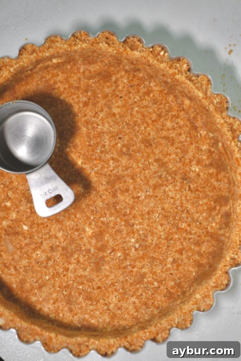 Creamy Banana Dream Pie 5 The Nilla wafer crust mixture being firmly and evenly pressed into the base and sides of a deep tart pan, creating a perfect foundation for the pie.