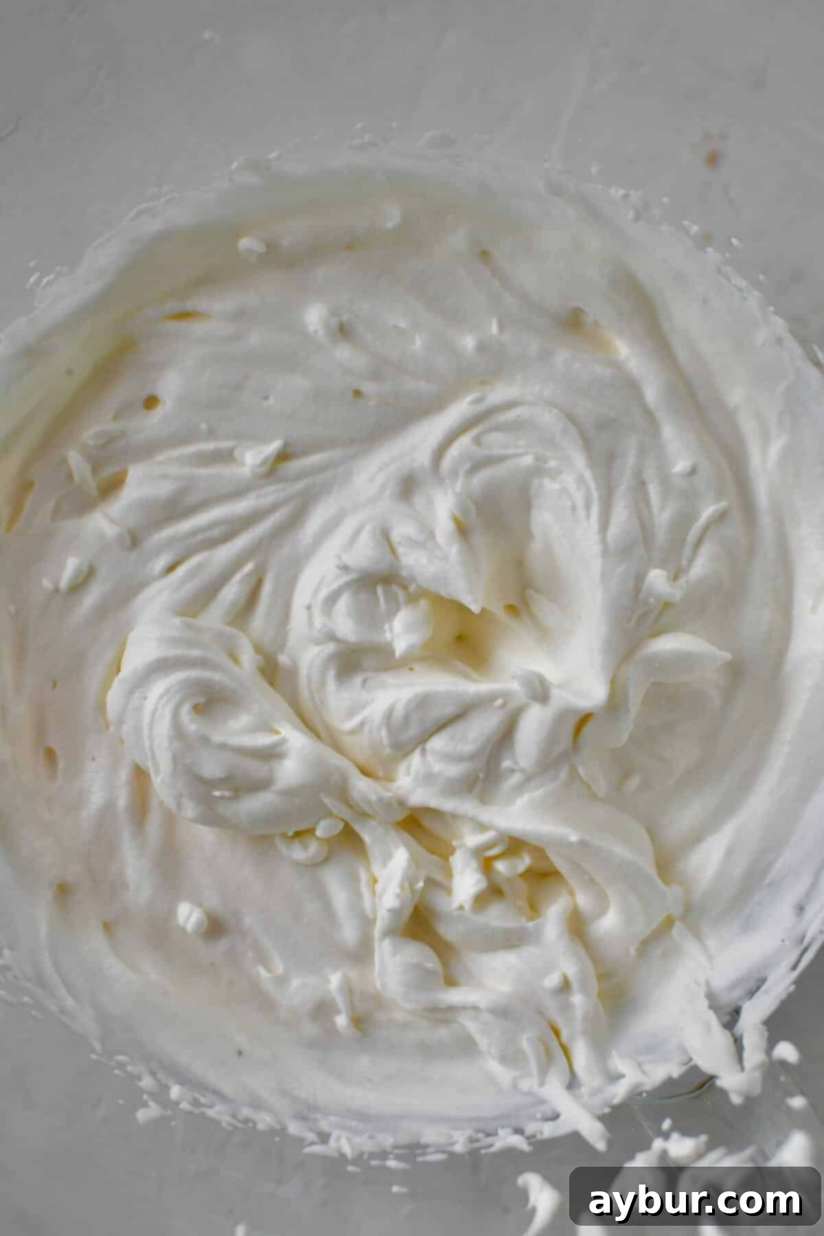First step of preparation: heavy cream being whipped in a stand mixer bowl until light and airy.