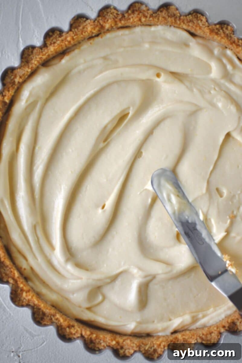 Spreading the first half of the banana pudding filling into the perfectly cooled Nilla wafer pie crust.