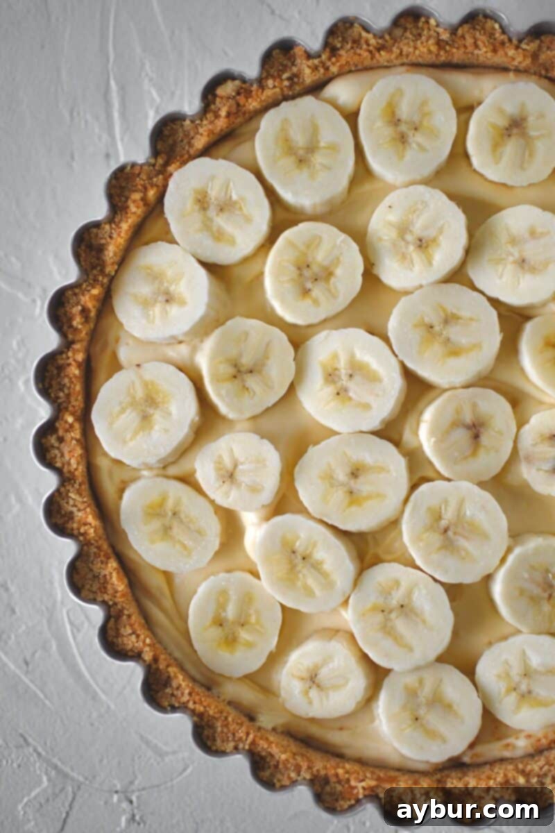 Creamy Banana Dream Pie 10 Arranging a neat and full layer of freshly sliced ripe bananas over the first layer of pie filling, preparing for the top pudding layer.