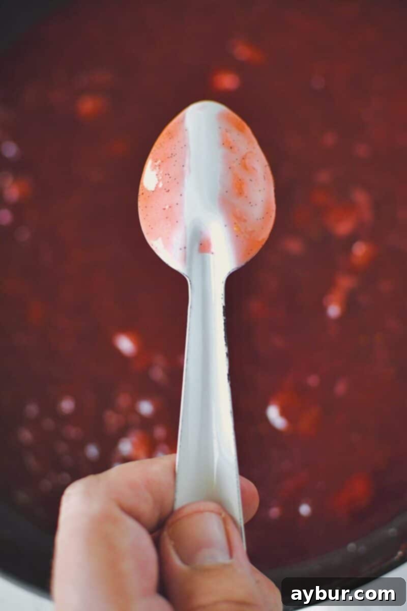 Sun-Kissed Strawberry Rhubarb Spread 10 A perfect example of cooked jam on the back of a spoon, showing a clear, enduring line when a finger is drawn through it, signifying ideal thickness and setting point.