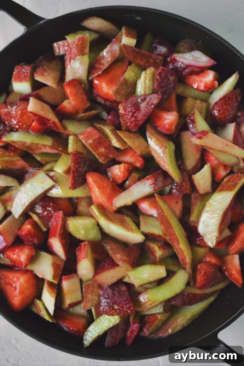 All the vibrant fruit and sugar-cornstarch mixture tossed together in a large bowl, ready to be transferred to the baking dish for the Strawberry Rhubarb Crisp.