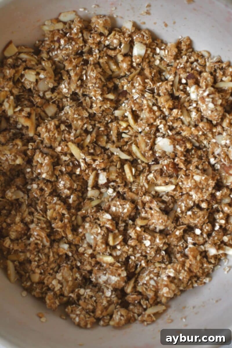 The crisp topping ingredients, including oats, brown sugar, butter, and almonds, perfectly mixed and crumbled in a large bowl.