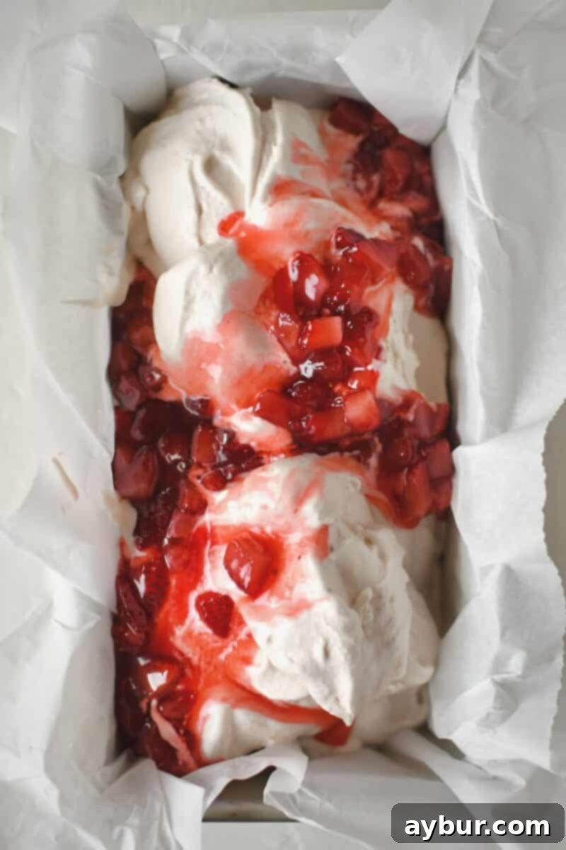 Strawberry Delight 13 Carefully mixing the warm, cooked strawberries into the freshly churned ice cream within a freezer-safe storage dish to create a marbled effect.