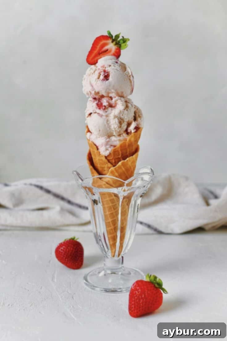 Scoops of homemade Strawberry Ice Cream in a waffle cone, ready for enjoyment.