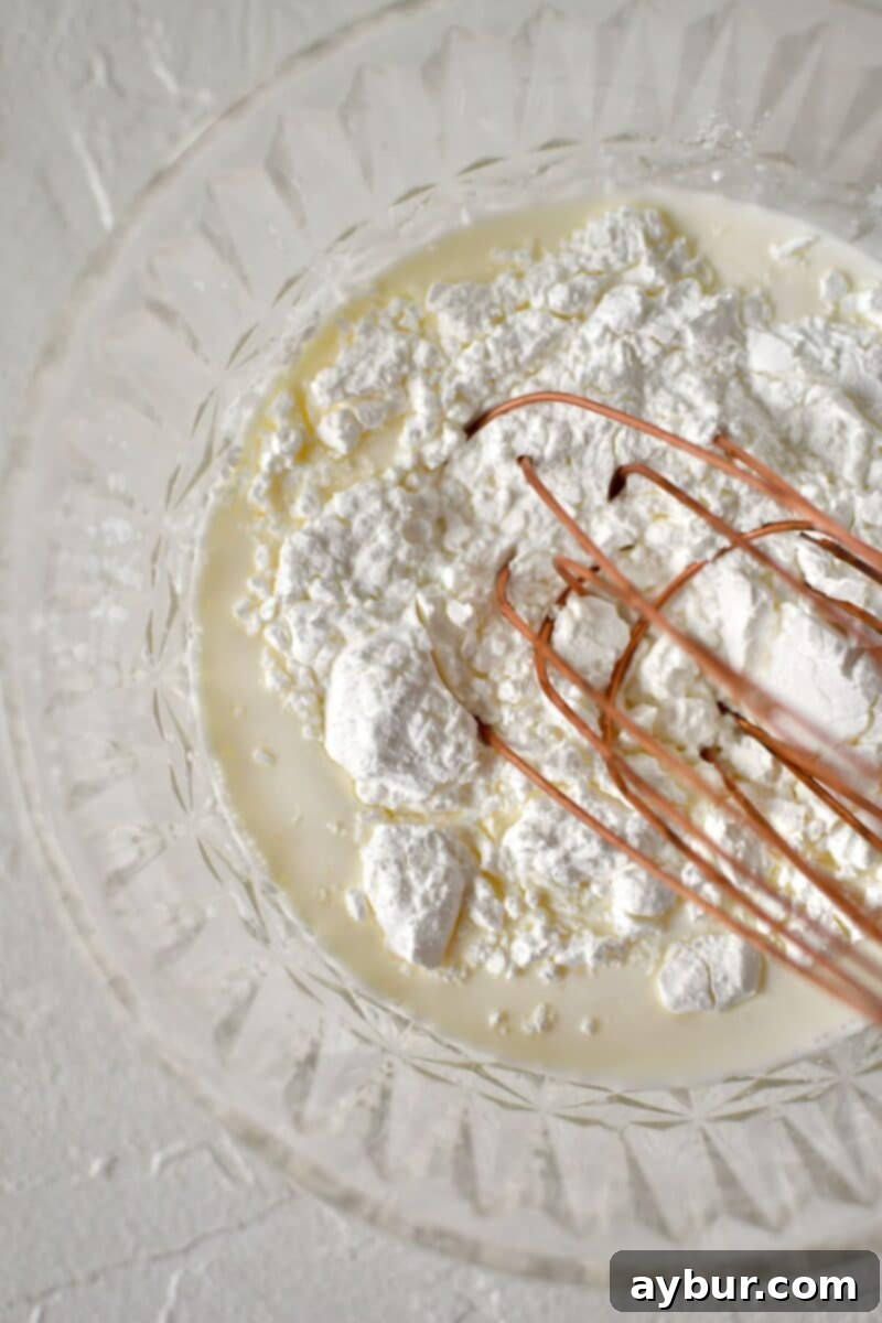 Strawberry Delight 4 Whisking together cornstarch and a portion of cream in a small bowl to create a smooth, lump-free slurry, an essential first step for an incredibly creamy ice cream.