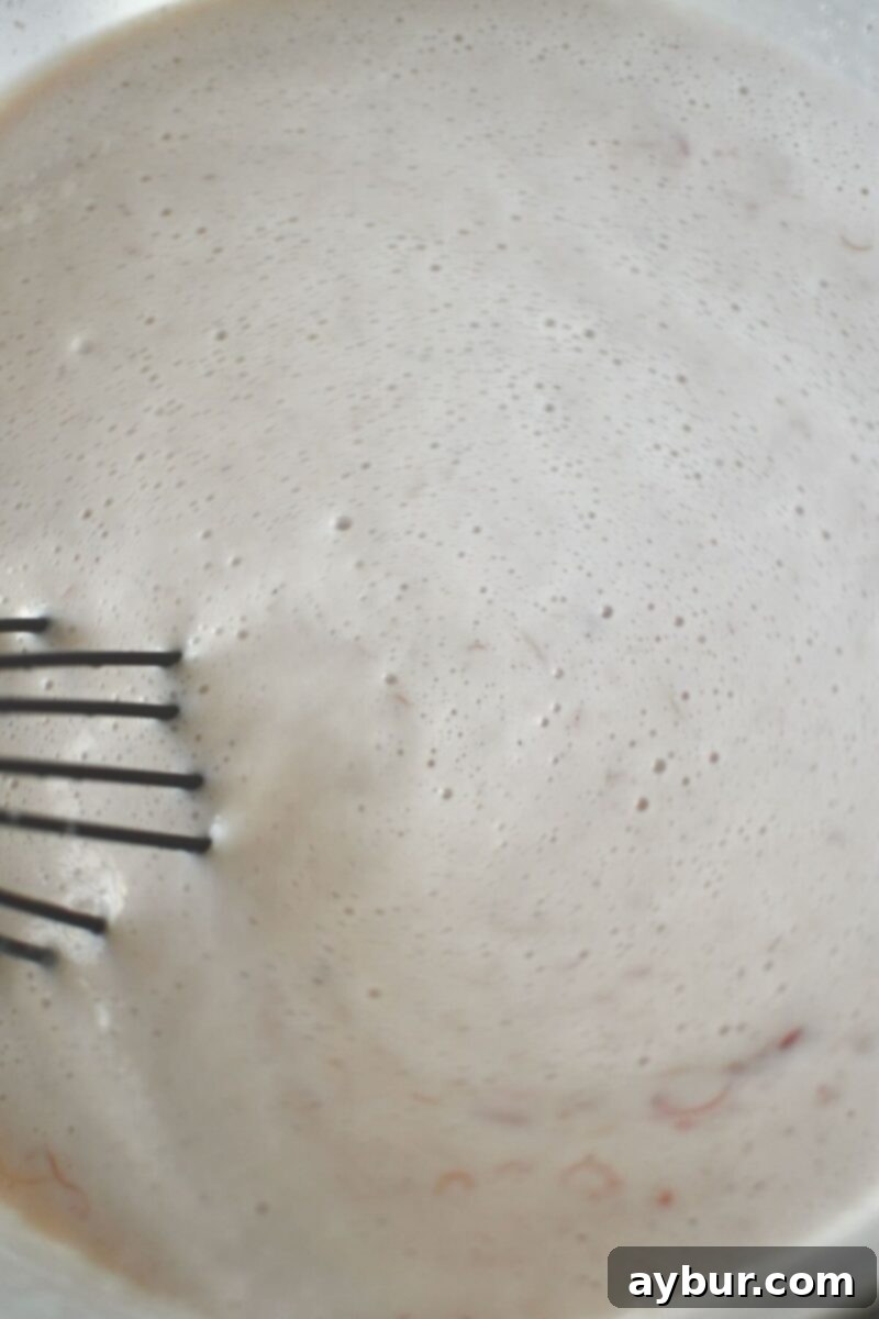 Strawberry Delight 8 Thoroughly whisking the well-combined ice cream base in a large bowl before chilling, ensuring all ingredients are fully integrated.