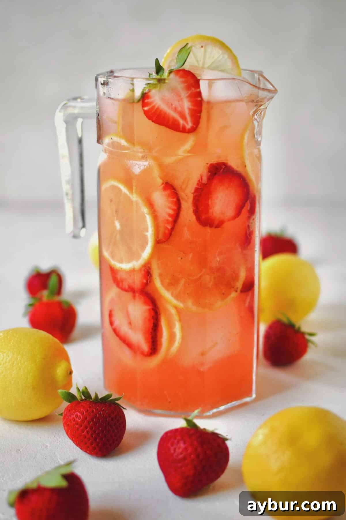 Sweet Strawberry Lemonade 7 Pitcher of Strawberry Lemonade ready to be poured and enjoyed, garnished with fresh fruit.