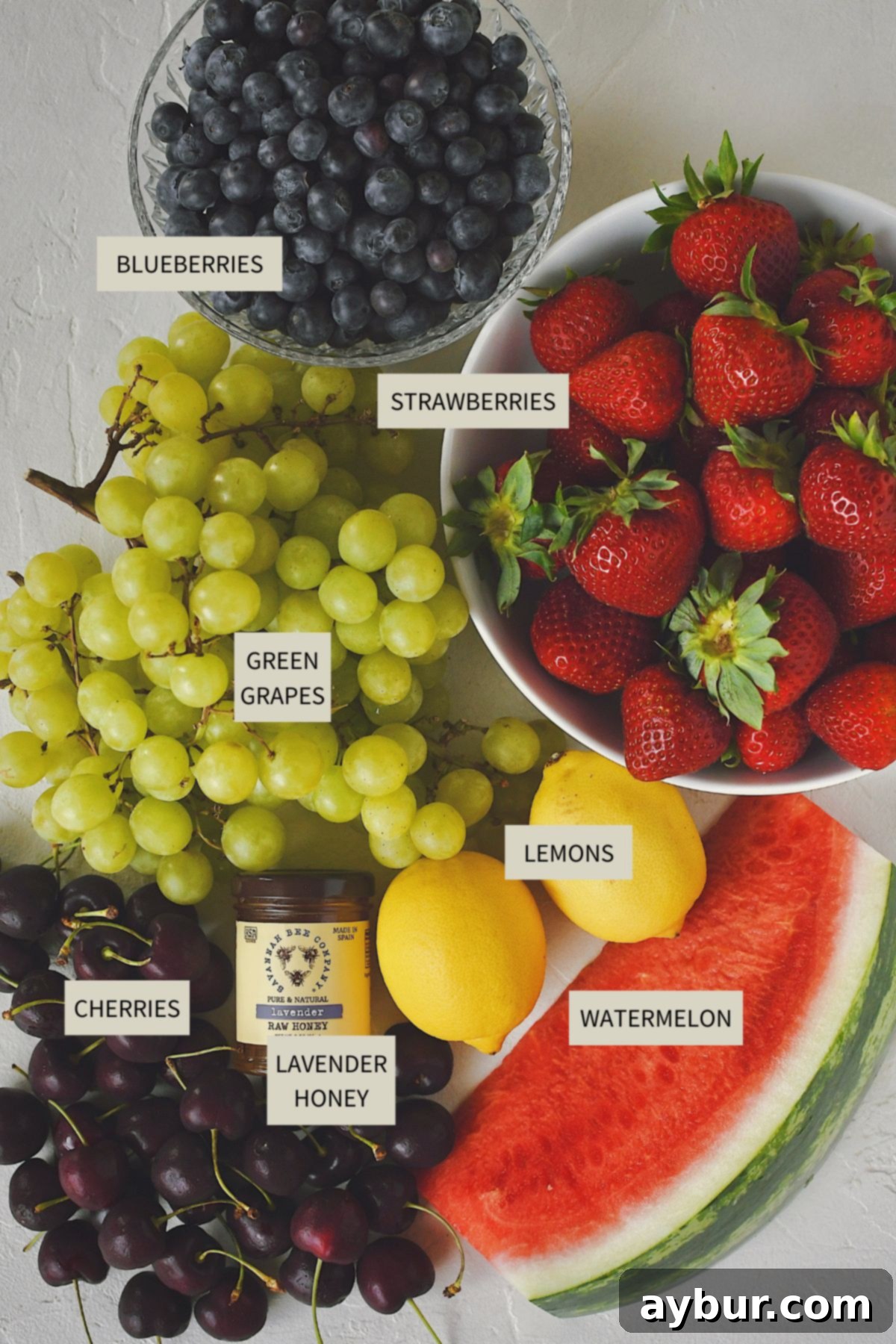 Assortment of fresh ingredients laid out on a table, including watermelon, grapes, cherries, strawberries, and blueberries, essential for making the Summer Fruit Salad.