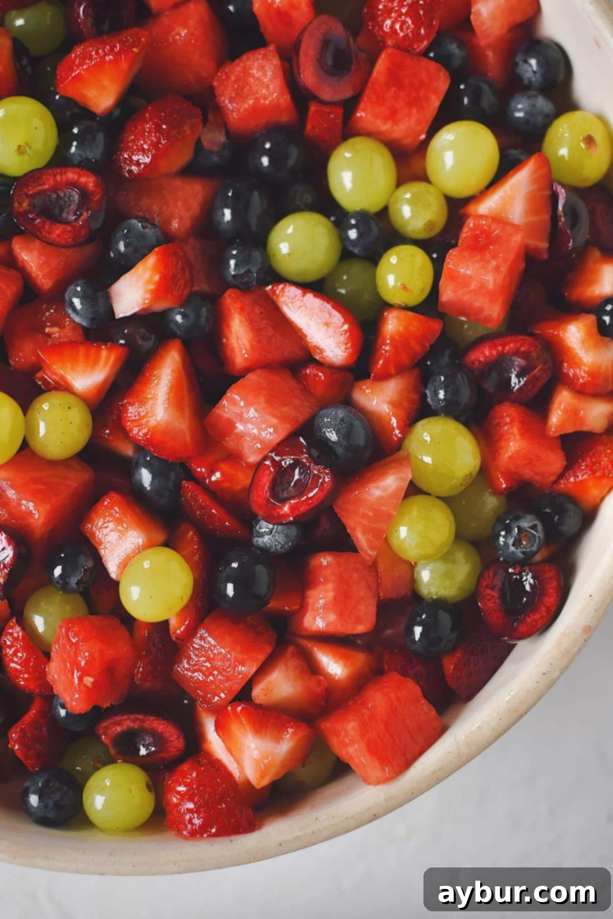 A generous bowl of Summer Fruit Salad with its vibrant colors and glistening dressing, ready to be served at a gathering.