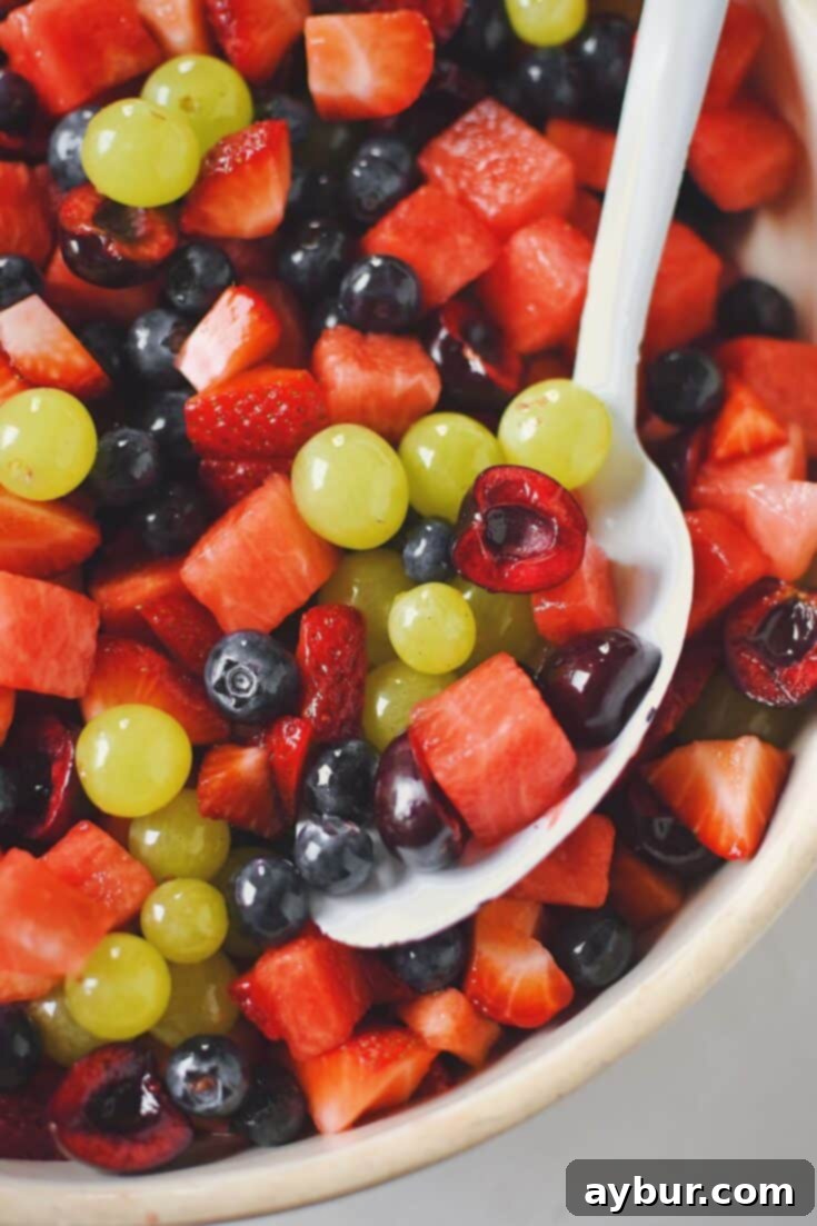 The finished Summer Fruit Salad, beautifully presented in a bowl, glistening with its lemon-honey dressing, ready to serve.
