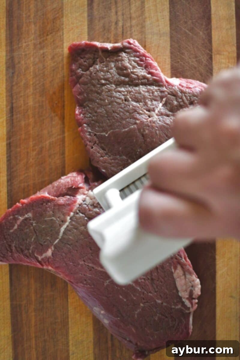 Tenderizing the sirloin steak with a Jaccard meat tenderizer, showing the tool being pressed into the meat.