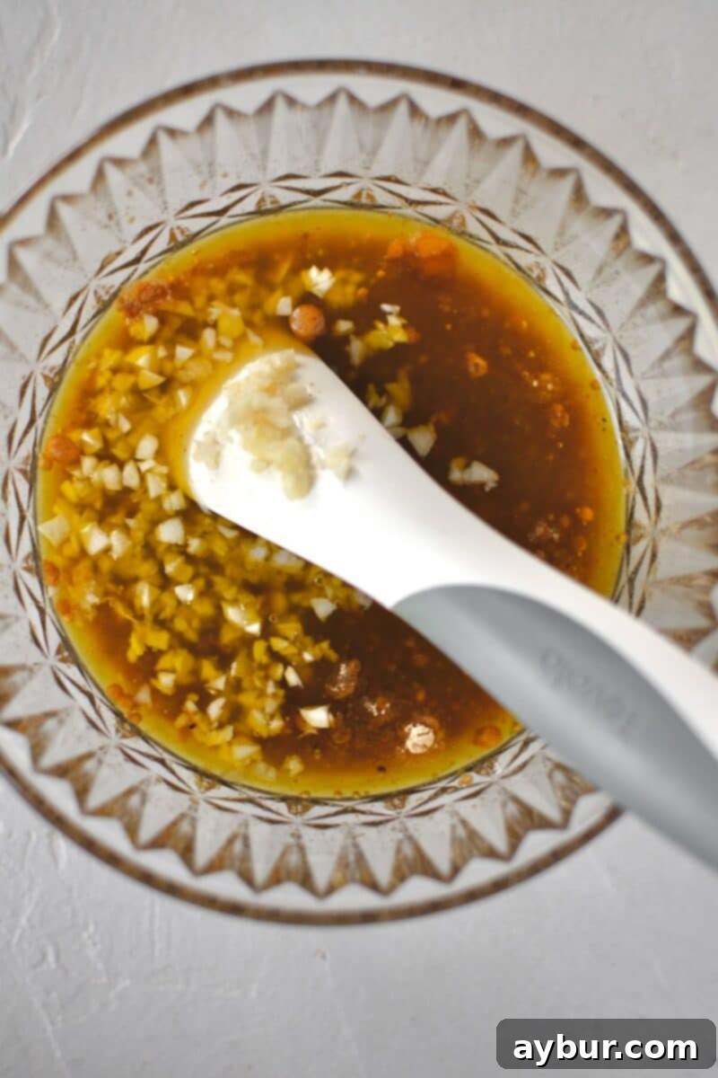 Mixing up the marinade ingredients in a bowl, showcasing the whisk combining the liquids and spices.
